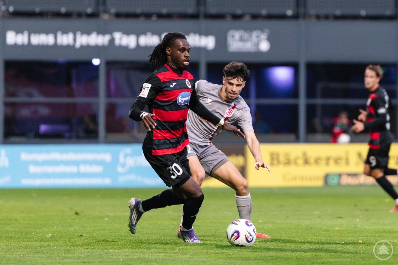 Beide Teams lieferten sich viele enge Zweikämpfe Spieler im grauen Trikot im Zweikampf mit einem Gegner im schwarz-roten Trikot nahe des Strafraums.