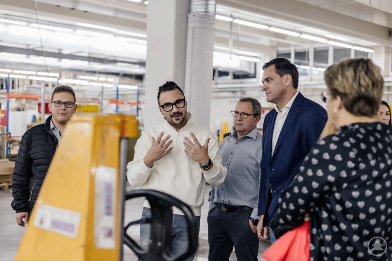 Landrat Sebastian Gruber (4. von links) im Rahmen einer Unternehmensführung in intensivem Austausch mit Rudolf (3. von links) und Fabian Schremmer (2. von links) von B&S Blech mit System GmbH & Co. KG in Grafenau. Landrat Sebastian Gruber und mehrere Personen werden in einer Produktionshalle von einem Mitarbeiter über Abläufe informiert.