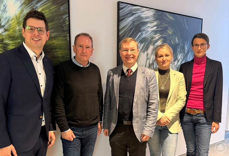 Bürgermeister und VG-Vorsitzender Martin Pichler (v.l.) und Geschäftsleiter Helmut Hörtreiter freuten sich ebenso über den neuen kommunalen Finanzmanager Sebastian Schlutz wie Personalerin Diana Prinz und Bauamtsleiterin Carina Weber. Fünf Personen stehen nebeneinander und blicken freundlich in die Kamera. Im Hintergrund hängen moderne, abstrakte Kunstwerke an der Wand. Die Personen tragen überwiegend formelle Kleidung, teils mit Sakko, Blazer oder Hemd.