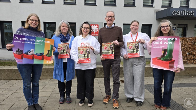 Team der Gemeindecaritas und Pastorale Dienste Mitarbeitende der Caritas stehen vor dem Caritas-Gebäude und halten Plakate zur Frühjahrssammlung mit dem Motto Zusammen geht was in den Händen.
