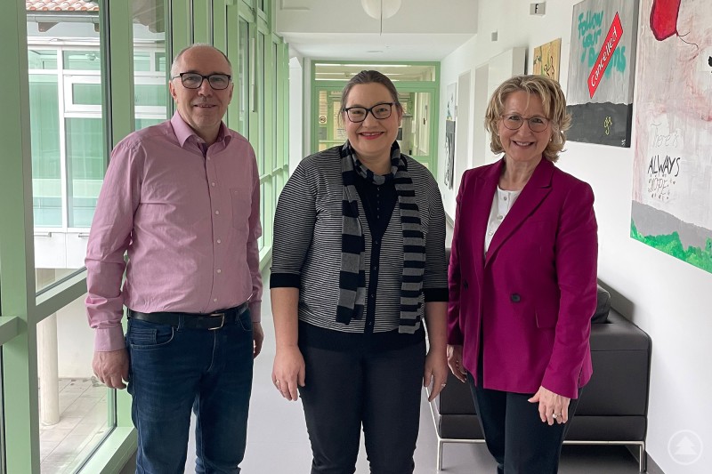 Bezirksrätin Monika Maier r bedankte sich bei der Gesamt-Schwerbehindertenvertretung des Bezirks Maria Stock sowie Lorenz Heilmeier vom Personalrat für ihr Engagement. Drei Personen stehen in einem hellen Flur des Bezirkskrankenhauses Landshut. In der Mitte steht die Gesamt-Schwerbehindertenvertretung Maria Stock, rechts Bezirksrätin Monika Maier und links Lorenz Heilmeier vom Personalrat.