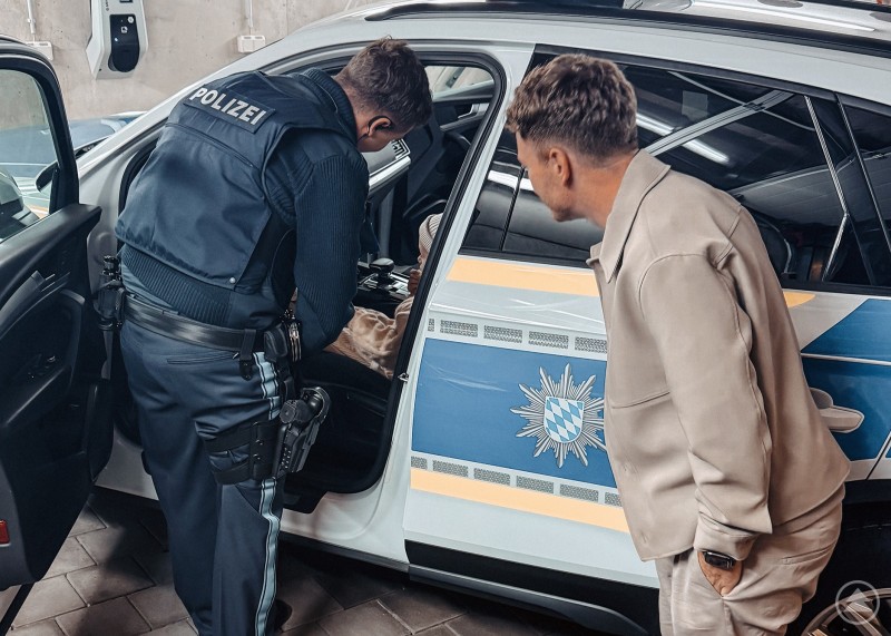 Auch die jüngsten Besucher kamen bei der Polizeiinspektion Grafenau voll auf ihre Kosten und durften sogar auf dem Fahrersitz Platz nehmen. Ein Polizist zeigt das Innere eines Streifenwagens, während ein Erwachsener danebensteht und zusieht.