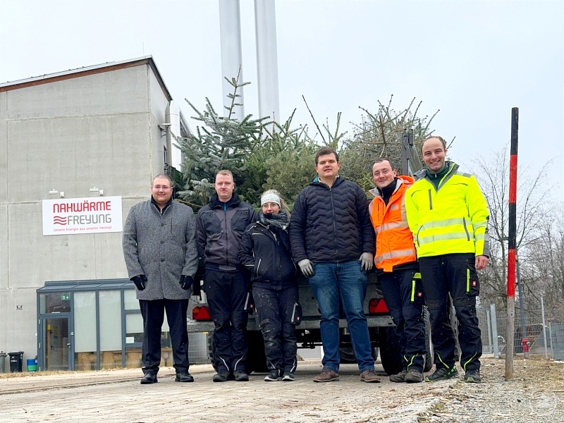 Hier werden die Christbäume ihrer weiteren Bestimmung zugeführt: (v. links n. rechts) Christoph Weishäupl, Benedikt Attenbrunner, Sabrina Brunner, Martin Höppler, Ludwig König und Dr.-Ing. Sebastian Weber mit einer Kipper-Ladung voller ausgedienter Christbäume vor dem Heizwerk der Freyunger Nahwärme.