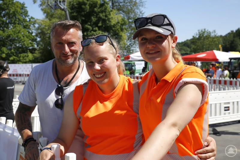 Die Icebreakers aus Bayreuth: Larina Zimmermann, Katharina Stake und Trainer Harald Blätterlein zeigten Einsatz und Teamgeist. Zwei junge Frauen in oranger Warnkleidung und ein Trainer posieren lachend mit Urkunde vor einem Schneepflug auf der Veranstaltungsfläche.