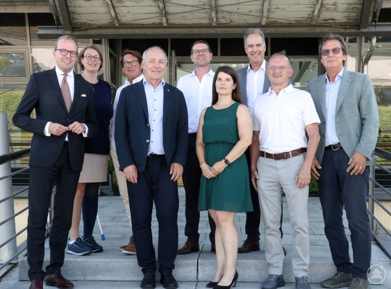 Die Mitglieder des IHK-Präsidiums Niederbayern bei ihrer Sommersitzung in Grafenau vor dem Firmengebäude der Greipl GmbH. Zehn Personen stehen in zwei Reihen vor einem Firmengebäude und blicken in die Kamera, einige in Anzug, andere in sommerlicher Kleidung.