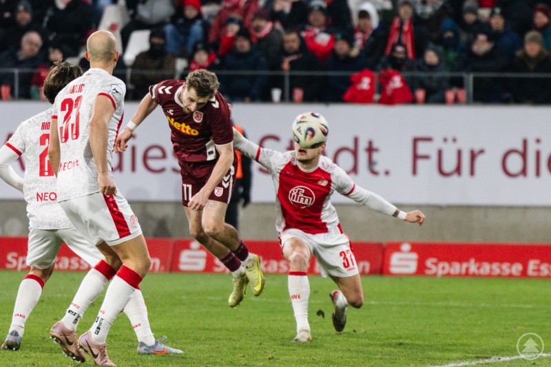 Kopfballduell im Strafraum beim Auswärtsspiel des SSV Jahn in Essen. Ein Regensburger Spieler steigt zwischen mehreren Essener Akteuren zum Kopfballduell hoch, der Ball ist auf Augenhöhe.