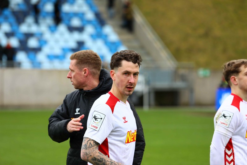 Adrian Fein nach der Partie des SSV Jahn Regensburg in Saarbrücken. Ein Spieler des SSV Jahn Regensburg in weiß-rotem Trikot steht nach dem Spiel auf dem Rasen, im Hintergrund sind ein Betreuer und Teile der Tribüne zu sehen.