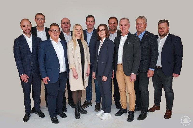 Die JWU FRG mit Kreistagskandidaten auf Platz 1-10 v. l.: StR Sebastian Weber, 3. Bgm. Christoph Endl, Jonas Höcker, Bgm. Roland Schraml, KRin Lisa Tiefenböck, LR Sebastian Gruber, Laura Dick, Kreisvorsitzender und 2. Bgm. Florian Eder, Bgm. Stefan Wagner, Bgm. Dirk Rohowski, Bgm. Heiner Kilger Gruppenfoto mit mehreren Personen in Anzügen, in der Mitte steht ein Mann, alle blicken in die Kamera vor hellem Hintergrund.