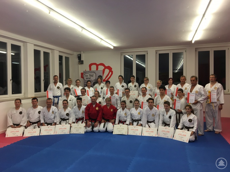 Hier sind die Junioren und Erwachsenen nach der Prüfung zu sehen. Neben den beiden Prüfern sitzen die Jugendschwarzgurt-Absolventen, Fabian Medl und Laura-Madeleine Sager