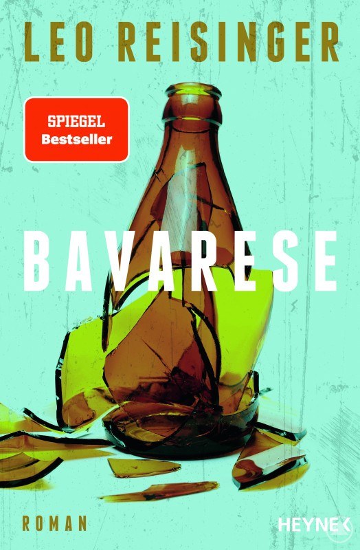 Leo Reisingers Debütroman „Bavarese“. Ein Buch mit dem Titel „Bavarese“ liegt auf einem Holztisch, daneben ein Glas Wasser.