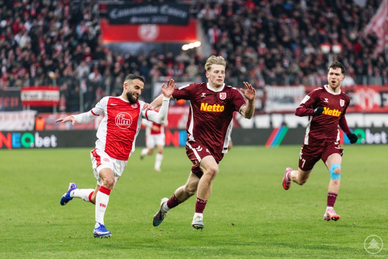 Der SSV Jahn Regensburg musste sich bei Rot Weiss Essen knapp mit 2:3 geschlagen geben. Mehrere Spieler sprinten dem Ball hinterher, die Tribünen im Hintergrund sind gut gefüllt.