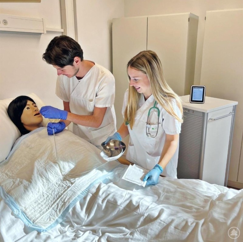 Praxisnah lernen: Im Nursing-Anne-Raum erleben Besucherinnen und Besucher moderne Pflegesimulationen. Zwei Auszubildende in Pflegekleidung üben an einer Pflegepuppe medizinische Handgriffe in einem modernen Simulationsraum.