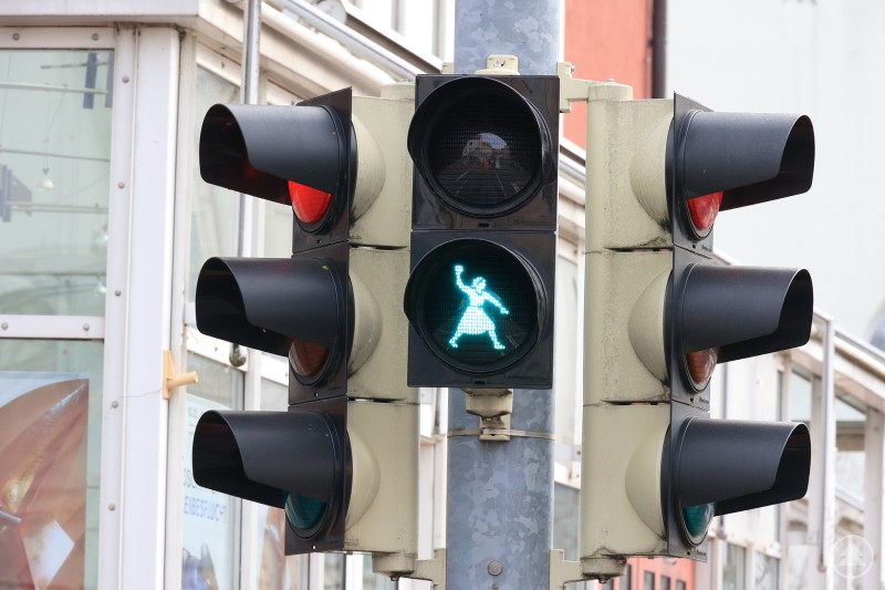 Die Knödelwerferin als grünes Signal an der neuen Motivampel in Deggendorf. Nahaufnahme einer Fußgängerampel. Das grüne Signal zeigt das Motiv der Knödelwerferin in bewegter Pose.