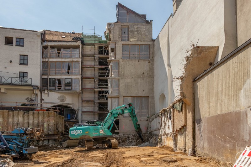 Blick auf die Rückseite eines teilweise entkernten Altbaus mit Bagger und Baugrube im Vordergrund. Der Altbau des St. Johannis-Spital-Stifts mit eingerüsteter Fassade und schwerem Baugerät für Unterfangungen.