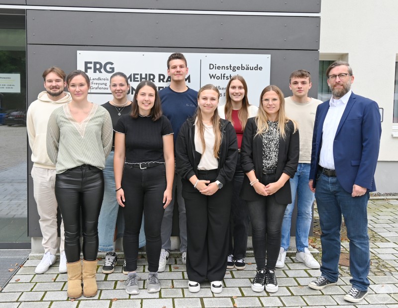 Konnten viel voneinander lernen: Die Praktikantinnen zusammen mit Anwärtern und Mitarbeitern des Landratsamts Freyung-Grafenau. Eine Gruppe junger Menschen, bestehend aus Praktikantinnen, Anwärtern und Mitarbeitenden des Landratsamts Freyung-Grafenau, steht vor einem Verwaltungsgebäude und blickt in die Kamera.