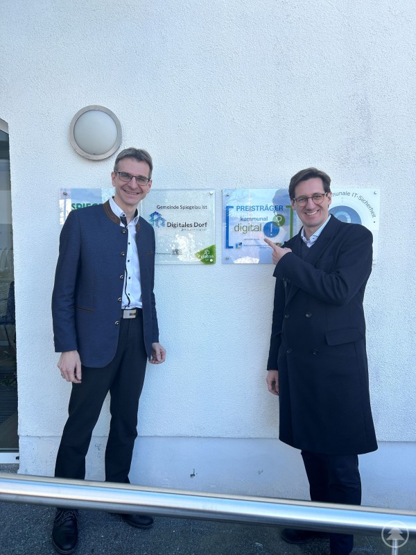 Digitalisierung als Erfolgsmodell: MdL Dr. Stefan Ebner und Spiegelaus Bürgermeister Karlheinz Roth tauschten sich über dieses Schlüsselthema und weitere Zukunftsaspekte aus. Der CSU-Landtagsabgeordnete Dr. Stefan Ebner und Spiegelaus Bürgermeister Karlheinz Roth stehen vor dem Rathaus Spiegelau neben mehreren Auszeichnungen zur Digitalisierung der Gemeinde, darunter „Digitales Dorf“ und „kommunal digital“.