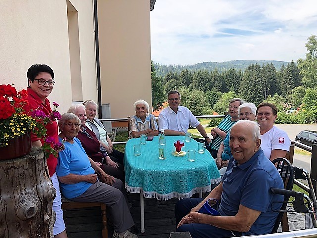 MdL Alexander Muthmann informiert sich über den Betreuungsdienst des Kreiscaritasverbandes Freyung-Grafenau. In Mauth genießen die Senioren den schönen Sommertag und schildern, was sie an dem Angebot schätzen. Links im Bild Leiterin Sonja Pangratz.