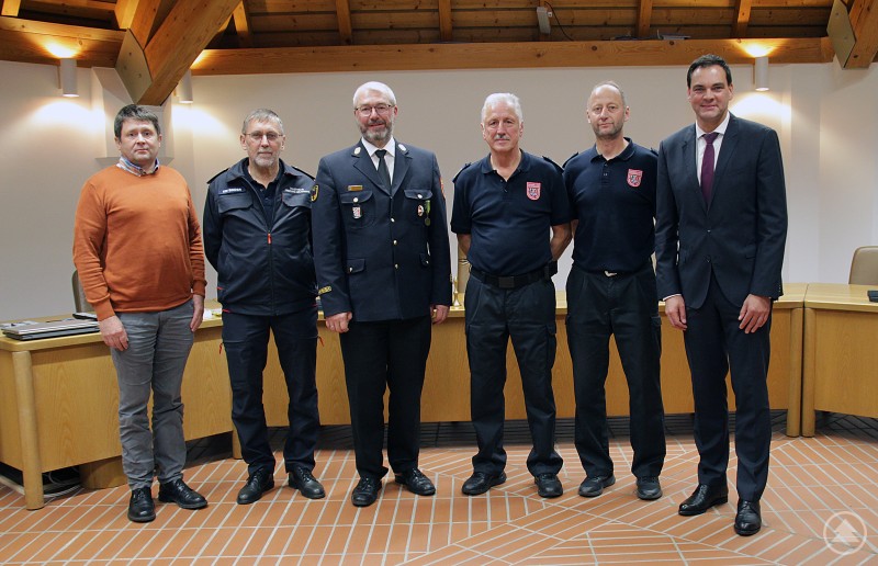 v.l.: Franz Stöbich (Sachgebietsleiter öffentliche Sicherheit und Ordnung), KBI Jürgen Binder, KBI Thomas Thurnreiter, KBR Norbert Süß (bis November 2025), der designierte KBR Martin Bauer (ab November 2025) und Landrat Sebastian Gruber Sechs Männer stehen in einem Sitzungssaal nebeneinander für ein Gruppenfoto. Einige tragen Dienstuniformen der Feuerwehr, andere sind in zivil gekleidet. Der Raum ist hell, mit Holzdecke und Tischen im Hintergrund.