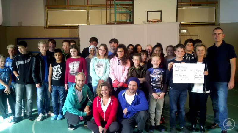 Die Schüler samt Schauspieler, Schulleiterin Dr. Hermine Englmeier mit dem Unterstützungs-Scheck von Böhmwind-Geschäftsführer Matthias Wagner (links).