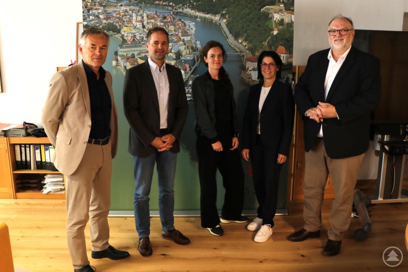 Oberbürgermeister Jürgen Dupper (v. rechts) begrüßt Martina Zitzelsberger und Laura Jonas im Beisein von Schulamtsdirektor Klaus Sterner und Referent für Wirtschaft und Bildung Werner Lang. Fünf Personen stehen in einem Büro vor einem Roll-Up mit Stadtansicht; alle sind formell gekleidet und lächeln in die Kamera.