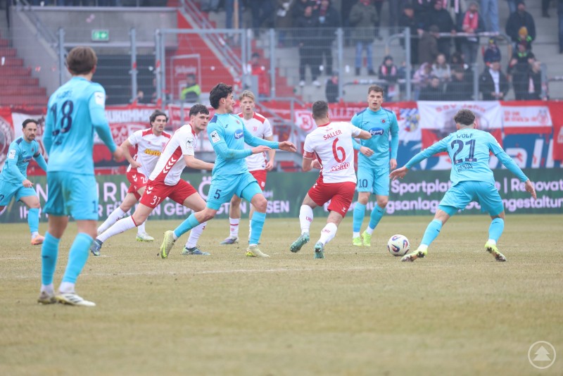 Zahlreiche Spieler beider Mannschaften stehen im Strafraum von Viktoria K&ouml;ln bereit. Ein K&ouml;lner Spieler kontrolliert den Ball, w&auml;hrend mehrere Jahn-Akteure auf den m&ouml;glichen Abschluss reagieren.