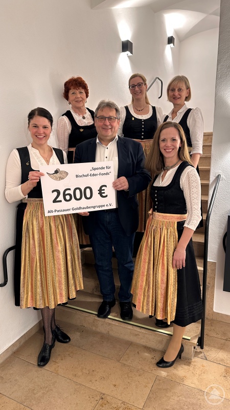 Golhaubengruppe-Spende-BEF - BU: Ein symbolischer Scheck für eine große Geste: Die Alt-Passauer Goldhaubengruppe spendet 2.600 Euro an Bischof-Eder-Fonds, vertreten durch Caritas-Vorstand und BEF-Kommissionsvorsitzenden Diakon Konrad Niederländer. Die Vorstandschaft der Goldhaubengruppe von links nach rechts: Katrin Vogl, Gunda Rankl, Sandra Nusser, Barbara Kreinlinger und Katrin Rankl.