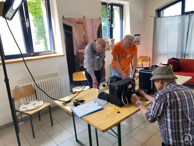 Die Ehrenamtlichen Helfer (v.l.) Christoph Brandl, Wolfgang Bogotz und Elmar Schwarzmaier bei der Reparatur einer elektrischen Heckenschere und eines Projektors.