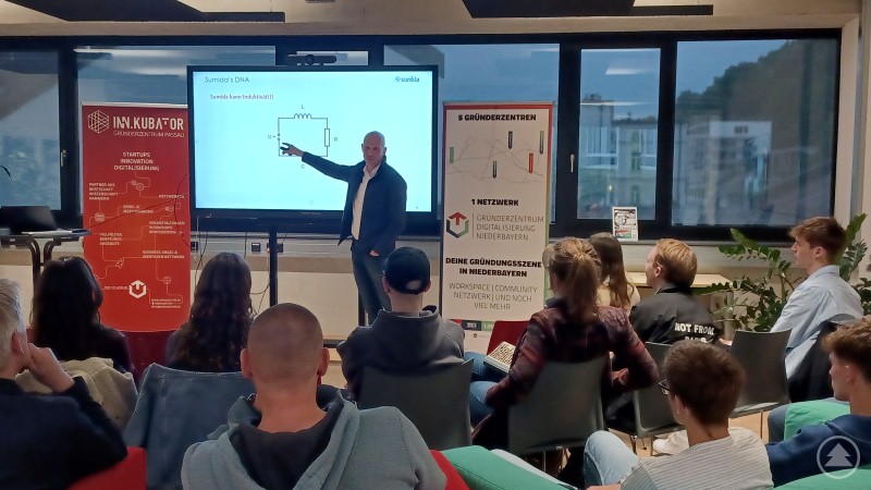 Vortrag im INN.KUBATOR Passau: Florian Weichselbaumer von labland.ai erläutert die Funktionsweise von KI-Agenten. Ein Referent steht vor einer Leinwand im Gründerzentrum INN.KUBATOR Passau und erklärt einem jungen Publikum ein technisches Schaltbild. Im Raum sind mehrere Zuhörerinnen und Zuhörer aufmerksam dem Vortrag folgend.