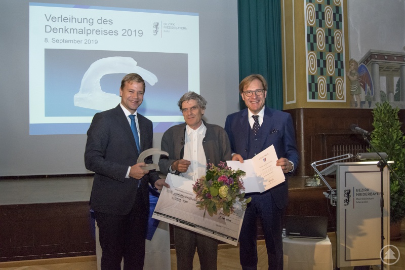 Bei der Verleihung des Denkmalpreises: Bezirkstagspräsident Dr. Olaf Heinrich (l.), Bezirkstagsvizepräsident Dr. Thomas Pröckl (r.) und der Preisträger Thomas Niggl.
