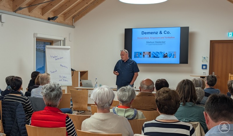 Referent Markus Haslecker beim ersten Vortrag in Konzell im September. Ein Referent steht vor einer Leinwand mit der Präsentation „Demenz & Co.“ und spricht vor einem voll besetzten Saal.