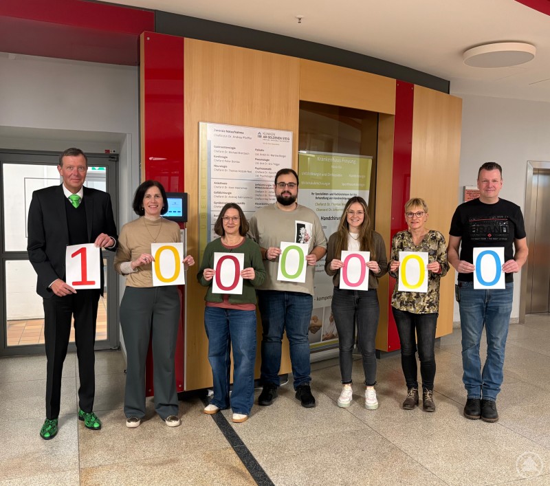 Eine Million Treppenstufen haben die Mitarbeiter der Kliniken Am Goldenen Steig im Rahmen der Treppenchallenge bereits gesammelt. Mehrere Mitarbeitende der Kliniken stehen im Eingangsbereich nebeneinander und halten Karten mit der Zahl 1000000 in den Händen.