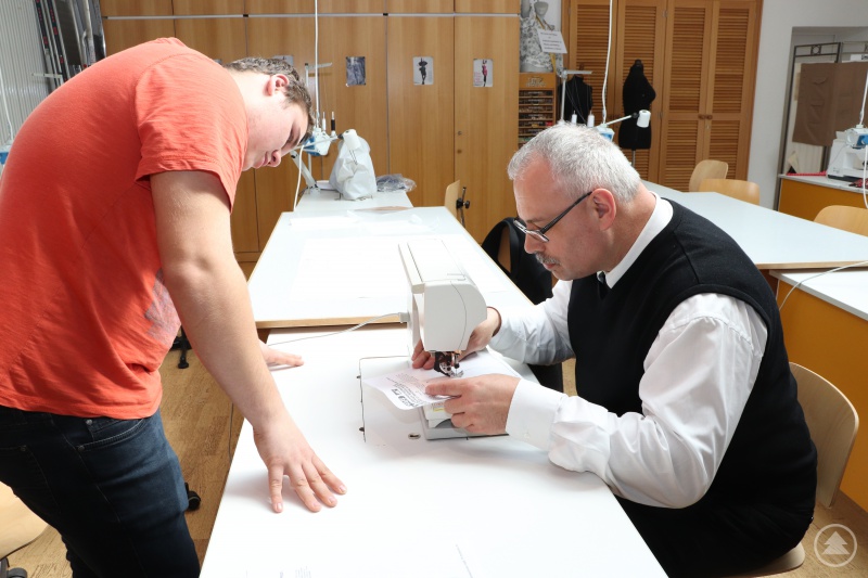Generalvikar Dr. Klaus Metzl konzentriert beim Nähen. Kevin Klinginger schaut genau hin.