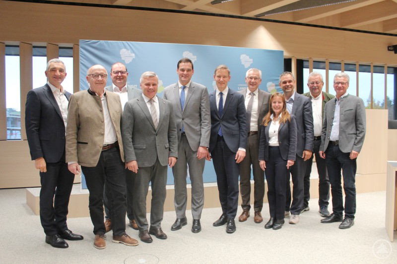 Die niederbayerischen Landräte tagten im neuen Landratsamt Landshut in Essenbach. Eine Gruppe von niederbayerischen Landräten steht im neuen Sitzungssaal des Landratsamtes Landshut in Essenbach zusammen. Die Anwesenden blicken in die Kamera, im Hintergrund ist ein hellblaues Banner mit dem Logo des Landkreises Landshut zu sehen.