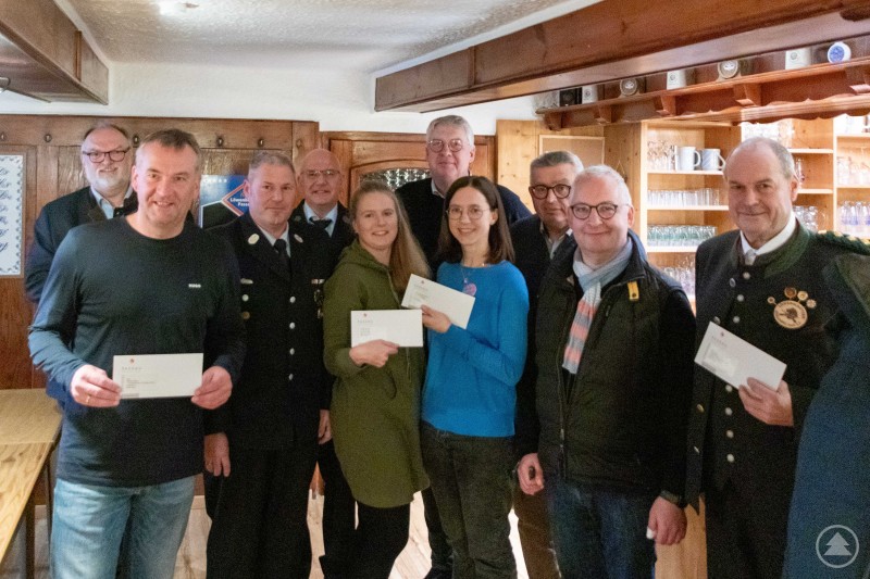 Oberbürgermeister Jürgen Dupper (1. v. links) bei der Übergabe der Spendenbriefe an Vertreterinnen und Vertreter aus Vereinen und Einrichtungen in Schalding rechts der Donau. Eine Gruppe von Männern und Frauen steht in einem holzgetäfelten Raum und hält Umschläge in den Händen. Mehrere Anwesende tragen Uniformen oder Tracht, in der Mitte stehen zwei Frauen, vorne links und rechts werden Umschläge präsentiert. Die Stimmung ist freundlich, es handelt sich um eine Spendenübergabe.