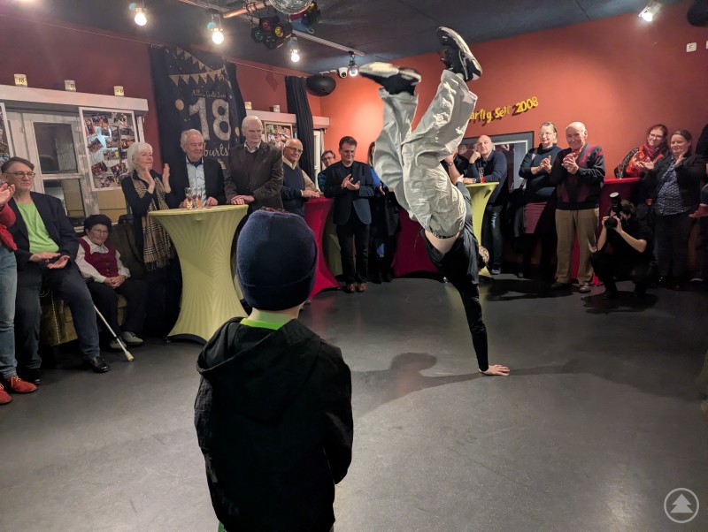 Breakdancer f&uuml;hrt einh&auml;ndigen Handstand vor klatschendem Publikum vor