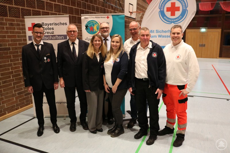 Oberbürgermeister Jürgen Dupper (4. v. l.) bei der Verleihung zusammen mit Andreas Schwarz (Wasserwacht OG Passau-Hals / 40 Jahre), Anton Ganczer (Wasserwacht OG Passau-Hals / 50 Jahre), Stefanie Stogel (Ortsgruppenleiterin Wasserwacht OG Passau-Hals), Susanne Schirmer (Ortsgruppenleiterin Wasserwacht OG Ilzstadt-Salzweg), Ulrich Lang (Wasserwacht OG Ilzstadt-Salzweg / 50 Jahre), Paul Salomon (Wasserwacht OG Ilzstadt-Salzweg / 50 Jahre), Thomas Hofherr (Rotkreuz-Bereitschaft Passau II / 25 Jahre). Gruppenfoto mit Oberbürgermeister Jürgen Dupper und mehreren geehrten Mitgliedern des Bayerischen Roten Kreuzes sowie der Wasserwacht in einer Turnhalle. Die Geehrten stehen nebeneinander vor Roll-Ups des BRK und der Wasserwacht und tragen teilweise Uniformen oder Dienstkleidung.