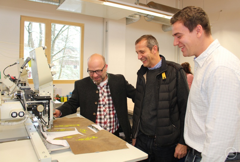 Karlheinz Freund (v.l.) erklärt Helmut und Florian Homolka die vollautomatische Stickmaschine.