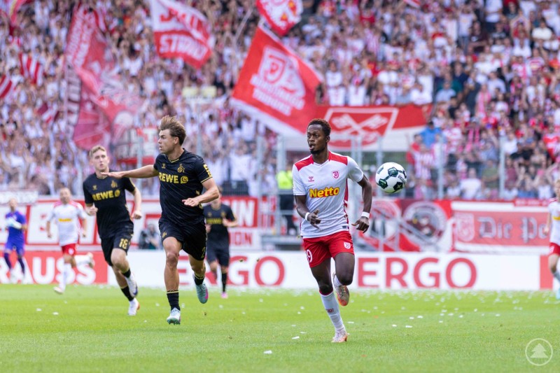 Der SSV Jahn Regensburg setzt mit schnellen Angriffen den 1. FC Köln unter Druck. Spieler des SSV Jahn Regensburg sprintet mit Ball am Fuß, ein Kölner Spieler verfolgt ihn eng.