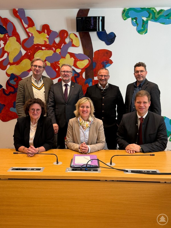 Dr. Olaf Heinrich (re. vorne) und Franz Dullinger (re. hinten) waren zu Gast beim Arbeitskreis Ernährung, Landwirtschaft, Forsten und Tourismus unter der Leitung von MdL Petra Högl (vorne Mitte). Sieben Personen – vier stehend, drei sitzend – posieren an einem Konferenztisch in einem modernen Tagungsraum. Im Hintergrund ist eine bunte, abstrakte Wandgestaltung zu sehen.