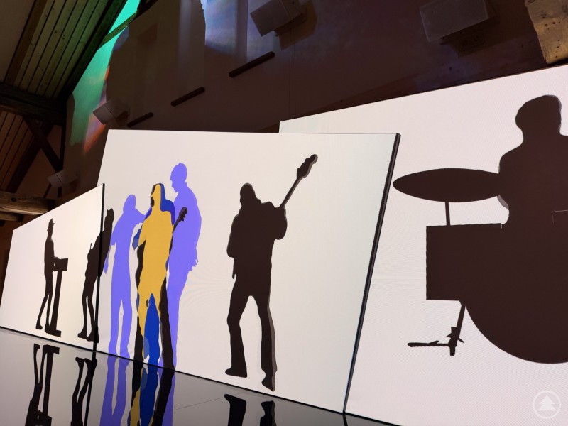 Künstlerisch inszenierte Musiker-Silhouetten zeigen den kreativen Zugang zur Landesausstellung „Musik in Bayern“. Mehrere große Tafeln mit stilisierten Silhouetten von Musikern und Instrumenten, teilweise farbig hinterlegt. Die Szene wirkt modern und künstlerisch inszeniert.