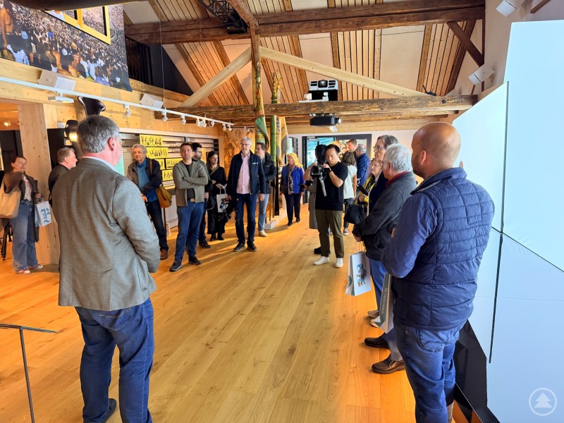 Besuchergruppe in einem Ausstellungsraum, die aufmerksam einer F&uuml;hrung zuh&ouml;rt.