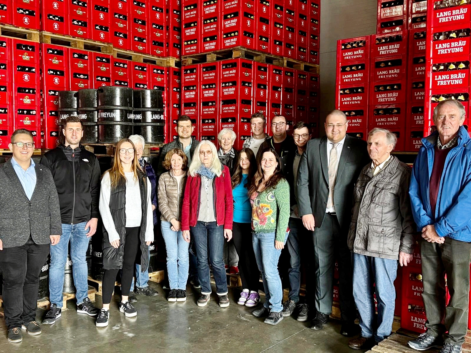 Die Vertreter des Kreisausschusses der Jungen Union Freyung‑Grafenau sowie der Kolpingsfamilie Freyung e.V. um JU-Kreisvorsitzenden und Kolping-Vorstandsmitglied Christoph Weishäupl (3. v. re.) in der Logistikhalle der Lang Bräu Freyung eG. Eine Gruppe von Personen steht in einer modernen Logistikhalle, darunter Mitglieder der Jungen Union und Kolpingsfamilie Freyung.