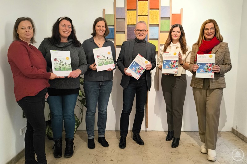 Über die neuen Bildungsangebote informiert das Team der Bildungsabteilung des Caritas-Diözesanverbandes Passau (v.li.): Denise Oberneder, Anna Slavicek, Teresa Rinner, Vorstand Stefan Seiderer, Christina Machleid-Loibl und Michaela Meindl. Sechs Personen stehen nebeneinander in einem hellen Raum und halten Broschüren des neuen Caritas-Bildungsprogramms in den Händen. Im Hintergrund hängt ein farbenfrohes Wandbild aus Holz- und Farbfeldern.