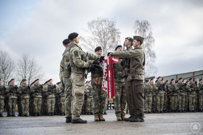 Eine Gruppe von Soldaten in Uniform legt während einer feierlichen Zeremonie gemeinsam ein Treuegelöbnis ab, im Hintergrund stehen Reihen weiterer Soldaten.