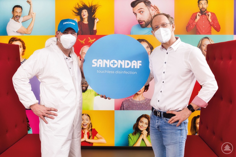 Franchisemaster Dr. Andreas Sachs (li.) überreicht nach der Testanwendung in der kieferorthopädischen Praxis Dr. Matthias Kiefl symbolisch ein übergroßes Desinfektionssiegel.