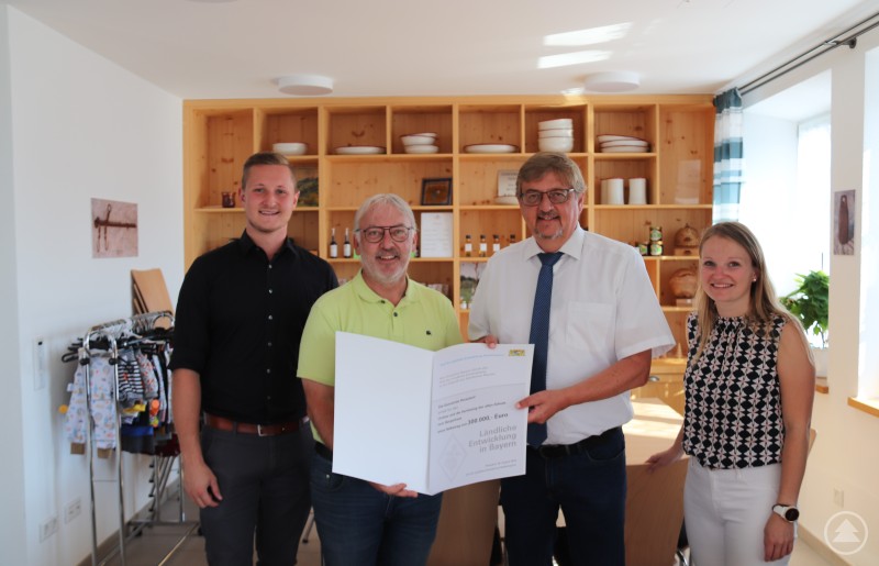 Der Leiter des Amtes für Ländliche Entwicklung (ALE) Niederbayern, Hans-Peter Schmucker (2.v.r.), überreicht im Dorfladen des Bürgerhauses an Perasdorfs Bürgermeister Thomas Schuster (2.v.l.) eine Auszahlungsurkunde über weitere 300.000 Euro. Mit auf dem Bild sind Bauamtsleiter Fabian Kilger (links) und stellvertretende Geschäftsstellenleiterin Veronika Schwarz von der Verwaltungsgemeinschaft Schwarzach.