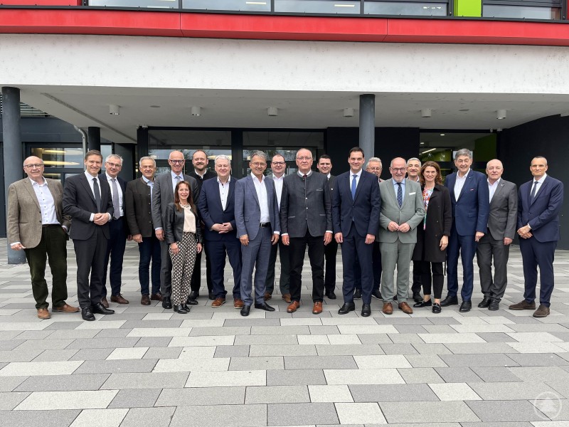 Eine Gruppe von etwa 20 Personen, darunter Landräte und Kammervertreter, steht für ein Gruppenfoto vor dem Eingang eines modernen Gebäudes.