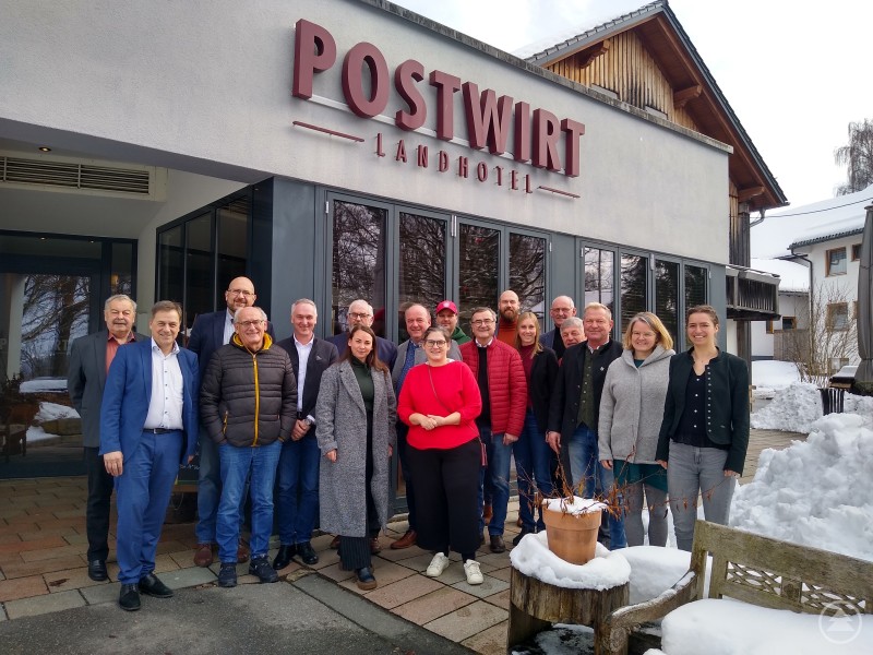 Die Beteiligten der ILE Ilzer Land blicken bei der Evaluierung zurück und zugleich in die Zukunft: Mit neuen Ideen kann die erfolgreiche Arbeit der ILE fortgesetzt werden. Im Bild v.l.: Werner Weny, 1. Vorsitzender der ILE Ilzer Land, 3.v.l. Sven Päplow und 1.v.r. Pia Waldbauer, beide vom Amt für Ländliche Entwicklung Niederbayern, mit der Bürgermeisterin und den Bürgermeistern der Ilzer-Land-Kommunen sowie deren Stellvertretern. Eine größere Gruppe von Männern und Frauen steht bei winterlichen Bedingungen vor dem Landhotel Postwirt. Alle sind freundlich zur Kamera gewandt, im Hintergrund ist Schnee zu sehen.