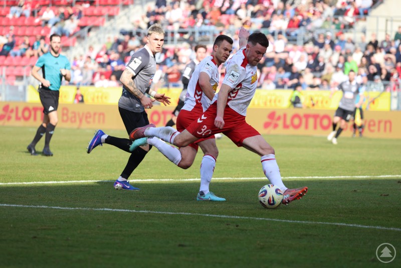Der Jahn ließ zahlreiche gute Möglichkeiten ungenutzt. Ein Regensburger Angreifer schließt im Strafraum ab, während ein Ulmer Verteidiger versucht zu blocken.