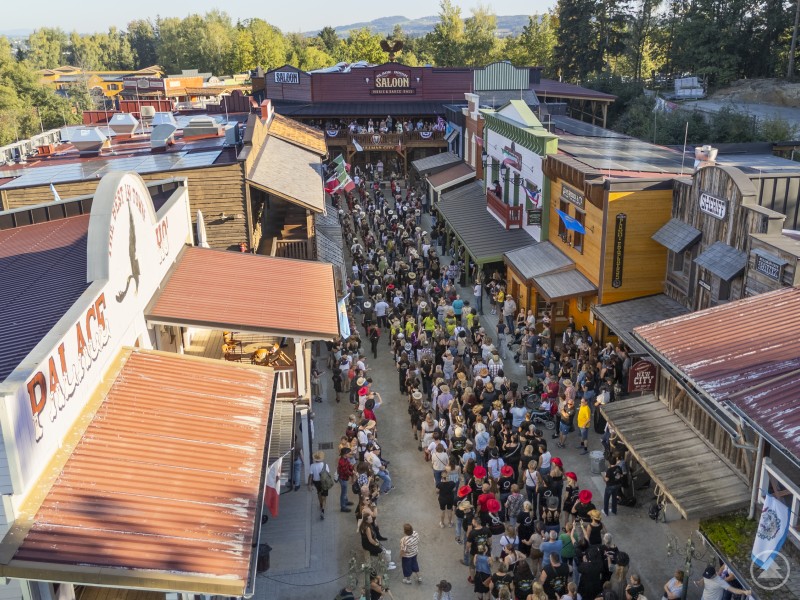 Line Dance soweit das Auge reicht: Die Main Street in Pullman City wurde beim Internationalen Line Dance Weekend 2025 zur größten Tanzfläche der Region. Luftaufnahme einer voll besuchten Westernstraße in Pullman City, wo hunderte Line Dancer dicht gedrängt tanzen.